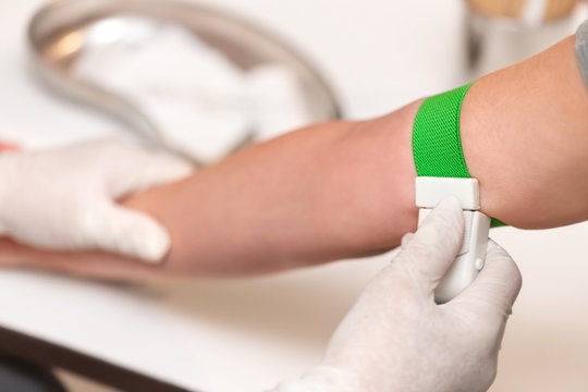 Arzt beim Anbringen von einem Venenstauer oder Staubinde an Patient