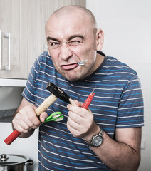 man in prime of life holds in teeth of screws and holding hammer