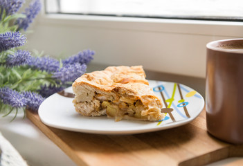 piece of pie with chicken and potatoes on a plate, lavender flowers, mug