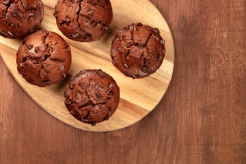Chocolate muffins, shot from the top on a dark rustic wooden background with copy space