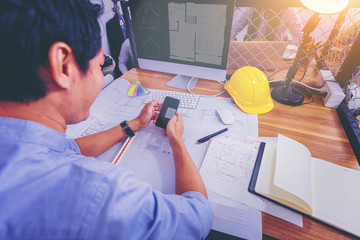 Architectures working sketching on blueprint for architectural project at construction site at desk in office.