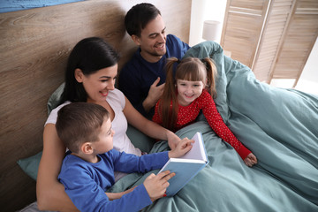 Happy family reading book in bedroom