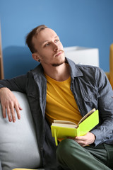 Handsome young man reading book at home