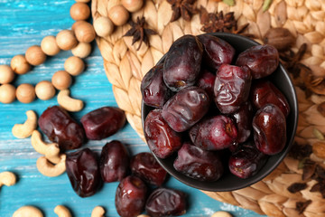 Bowl with tasty dates on wooden table