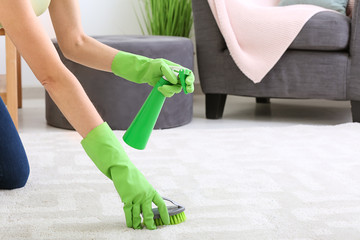 Young woman cleaning carpet at home