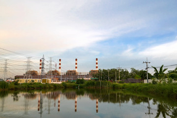 Fototapeta na wymiar Natural gas electric power plant with smokestack and many pole in chonburi thailand with water reflection and beautiful sky near evening