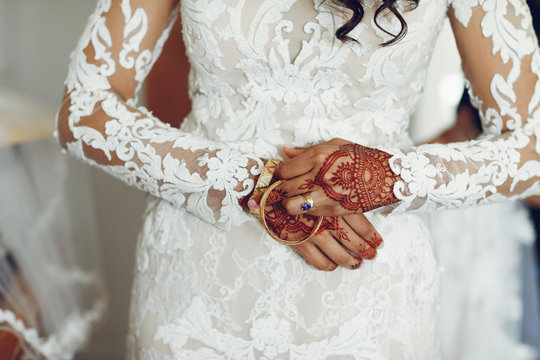 Beautiful bride in a white dress. Woman with gold bracelets. Lady with mehendi on her hands