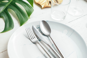 Silver cutlery with plate on white table