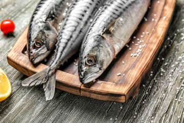 Board with tasty raw mackerel fish on wooden table