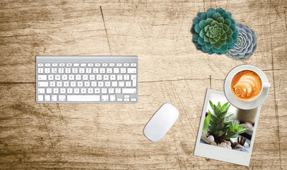 workers desktop with computer succulent coffee sample polaroid print mouse and keyboard wood