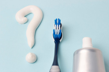 Question mark from toothpaste and toothbrush on blue background, choice concept