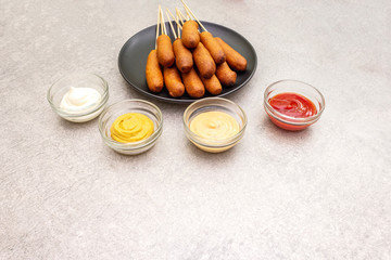 Corn dogs homemade with popular sauces. Traditional American street food. On stone background