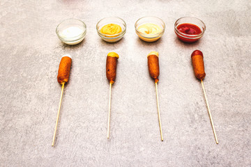 Corn dogs homemade with popular sauces. Traditional American street food. On stone background