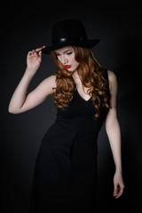 Fototapeta na wymiar Beautiful Woman in big black hat on dark background