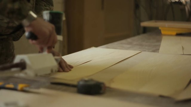 Carpenter Joiner splices veneer stripes with manual machine for gluing veneer in furniture workshop