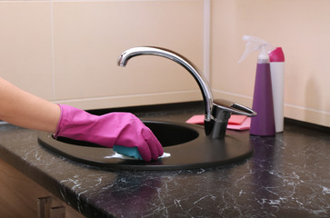 Young woman cleaning sink in bathroom