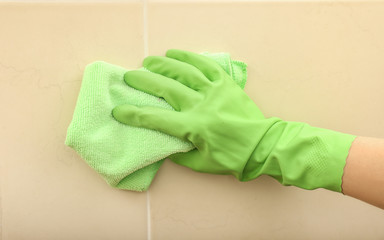 Young woman cleaning tiles in bathroom