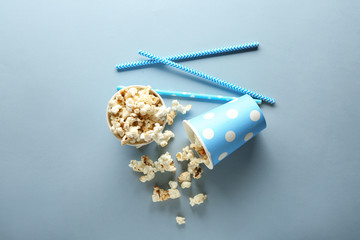 Paper cups of tasty popcorn on color background
