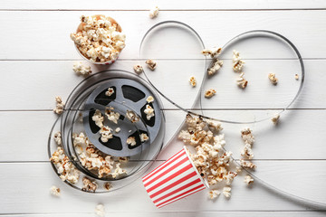 Composition with film reel and popcorn on wooden background
