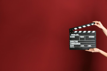 Female hands with cinema clapperboard on color background
