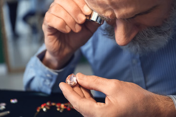 Jeweller examining gemstone in workshop, closeup