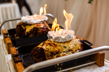 Delicious meat in fire at wedding reception in restaurant. Chef cooking tasty meal with fire show, luxury catering. Smoked meat in flames. Thanksgiving feast