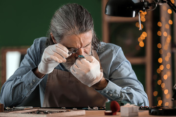 Jeweller examining adornment in workshop