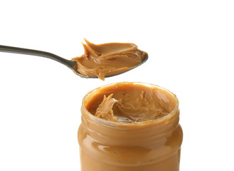 Jar and spoon with tasty peanut butter on white background