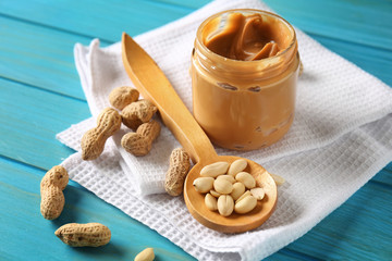 Jar with tasty peanut butter on wooden table