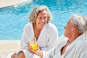 Senioren Paar mit einer Erfrischung am Pool