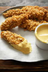 Tasty nuggets with sauce on wooden board