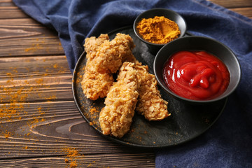 Plate with tasty nuggets and tomato sauce on wooden table