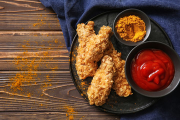 Plate with tasty nuggets and tomato sauce on wooden table