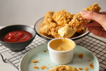Woman eating tasty nuggets with sauce, closeup