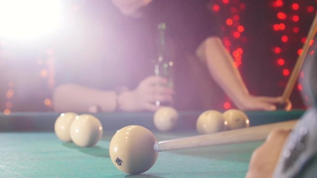 Billiards club. A person playing billiards. A cue hitting the ball. A man drinking beer on the background