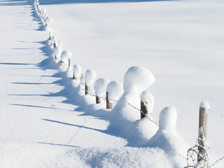 wooden barbed wire fence covered in snow