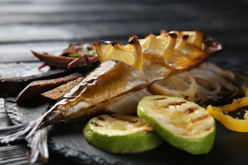 Grilled mackerel fish with garnish on slate plate