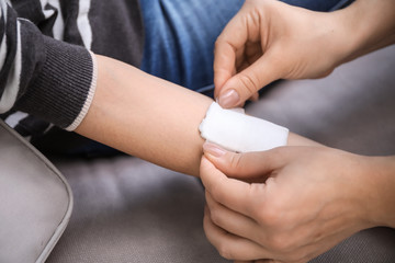 Providing of first aid to young woman with hurt arm, closeup