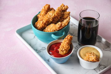 Tasty nuggets with sauces and glass of drink on tray