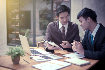 Image of two young asia businessmen using touchpad at meeting