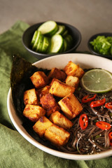 Bowl with tasty fried tofu cheese and soba noodles on table