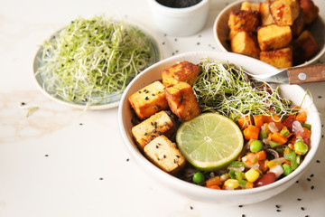 Bowl with tasty fried tofu cheese and vegetables on table