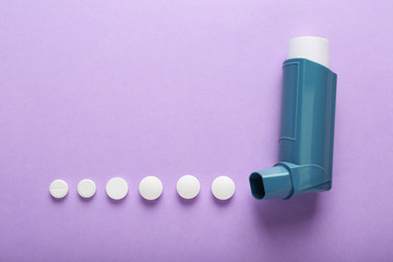 Inhaler and pills on color background