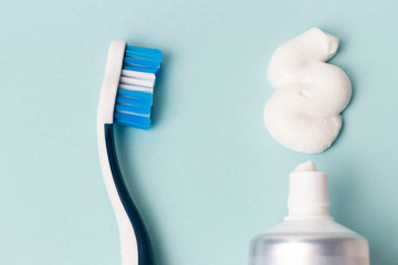 Toothpaste in tube and toothbrush on blue background. Dental hygiene concept.