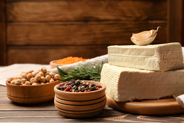 Tasty tofu cheese with spices on wooden background