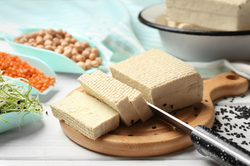 Cutting board with tasty tofu cheese on white table