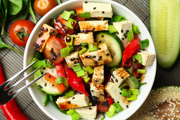 Healthy salad with tasty tofu cheese in bowl on table