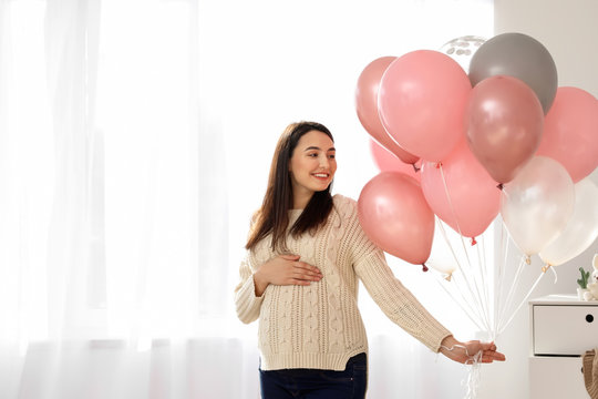 Beautiful pregnant woman with air balloons at home