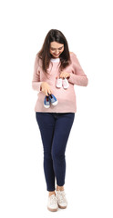 Portrait of beautiful pregnant woman with baby booties on white background