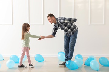Father and his cute little daughter dancing in room with balloons